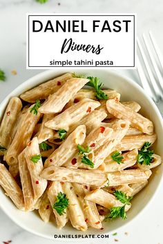 a white bowl filled with pasta and garnished with parsley on the side