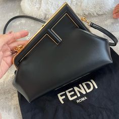 Small Fendi First Bag Made Of Soft, Black Nappa Leather With Oversized Metal F Clasp With Tone On Tone Nappa Leather Bands. Featuring An Internal Compartment Lined In An Iconic Ff Motif Fabric, Pull Out Internal Attachment Points And Gold-Finish Metalware. Can Be Carried By Hand As A Clutch Or Worn On The Shoulder Thanks To The Detachable Shoulder Strap. Made In Italy Composition 100% Lamb Leather, Inside: 27% Polyester, 27% Polyamide, 27% Polyurethane, 15% Cotton, 4% Resin Measurements Height: 18 Cm Depth: 9.5 Cm Width: 26 Cm Weight: 0.6 Kg Shoulder Strap Drop: 43 Cm Fendi First Small Bag Outfit, Fendi Crossbody Bag Cross Body Purses, Fendi Clutch Bag, Fendi Little Bag, Bags Wishlist, Fendi Purse, Fendi Tiny Bag, Fendi First, Fendi Clutch