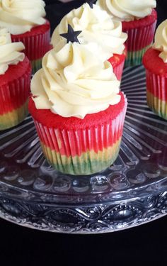 cupcakes with white and red frosting on a clear plate