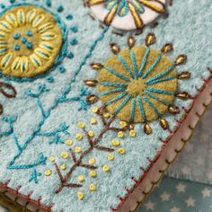 a close up of a cell phone case made out of felt and fabric with embroidered designs