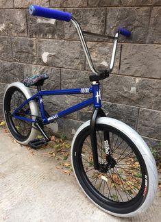 a blue and silver bicycle parked next to a brick wall with no wheels on it