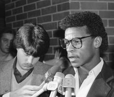 black and white photo of two men in front of microphones talking to each other