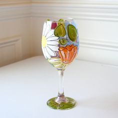 Hand Painted Wine Glasses These Hand Painted Wine Glasses are made by the artist in Portland, OR. The toned floral design has 4 different colored flowers surrounding a generously sized and sturdy 20 oz stemmed wine glass. Makes a wonderful gift for bridal showers, house warming, hostess present or any occasion for a favorite wine lover. Flower colors: White, orange, bright blue and purple. Hand washing is recommended. Due to the nature of each item being individually handmade, variations will oc Painted Wine Glasses Diy, Hand Painted Wine Glasses Diy, Wine Glasses Diy, Glass Painting Ideas, Wine Glass Art, Painting Glass, Hand Painted Wine Glasses, Painted Wine Bottles, Flower Colors