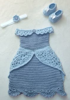 there is a crocheted dress and baby shoes on the floor next to it