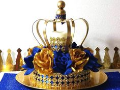 a golden crown with blue flowers on it sitting on top of a gold platter