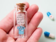 a hand holding a tiny glass bottle filled with confetti and an elephant on it