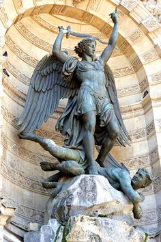 an angel statue holding a staff with two other statues around it