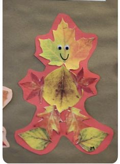 an autumn leaf cut out on top of a piece of paper with a smiley face