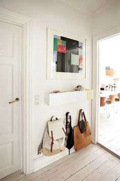 two purses are hanging on the wall in front of an open door with a table and chairs