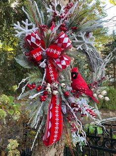 a red and white christmas wreath hanging on a tree