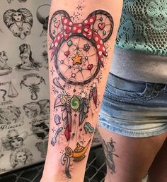 a person with a tattoo on their arm that has a mickey mouse head and dream catcher