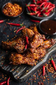 chicken wings with chili sauce and spices on a wooden cutting board next to other dishes