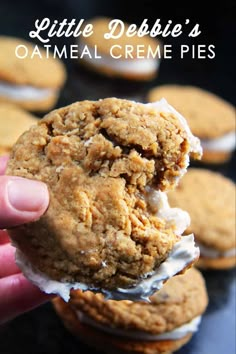 a hand holding up a cookie with white frosting on it and the words little debibie's oatmeal creme pies