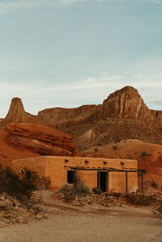 an adobe building in the desert with mountains in the background