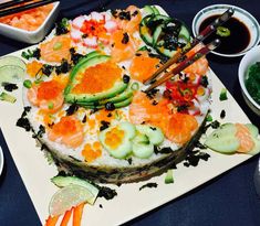 an assortment of sushi on a white plate with chopsticks and sauces