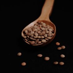 a wooden spoon filled with beans on top of a black table