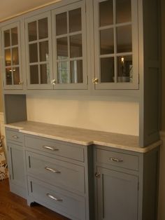 an empty kitchen with white cabinets and wood floors