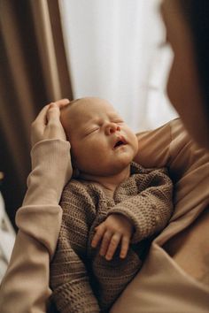 a woman holding a baby in her arms and looking at it's face as she sleeps