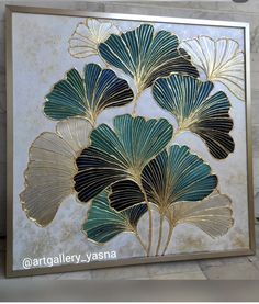 a painting with gold and green leaves on the wall in front of a brick wall