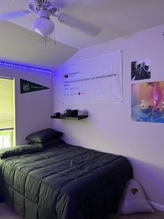 a room with a bed, ceiling fan and pictures on the wall above it is lit up by blue lights