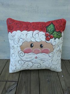 a decorative santa claus pillow on a wooden floor with wood planks in the background