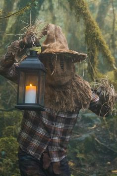 a scarecrow holding a lantern in the woods