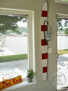 a red and white surfboard mounted to the side of a wall next to a window