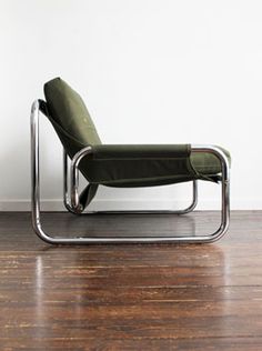 a green chair sitting on top of a wooden floor next to a white wall and wood floors