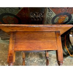 an old wooden table sitting on top of a floor next to other antique dishes and vases