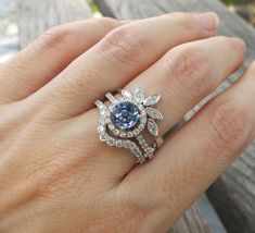 a woman's hand with a blue and white diamond ring on her left hand