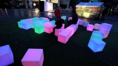 people are sitting and standing around glowing cubes