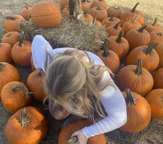 a woman is laying on the ground surrounded by pumpkins