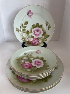 three plates with pink flowers on them stacked up in front of each other and one is empty