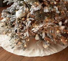 a white christmas tree with gold and silver ornaments on it's branches, sitting on a wooden floor