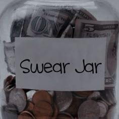 a jar filled with lots of money sitting on top of a table next to a sign that says swear jar