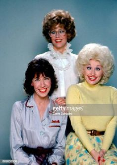 three women sitting next to each other in front of a blue wall