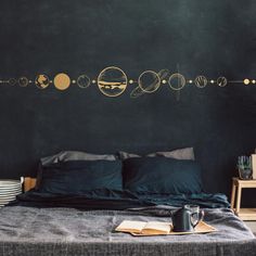 the solar system wall decal is shown above a bed with black sheets and pillows