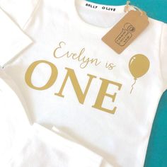 Gorgeously soft white cotton baby Pyjamas for their First Birthday! What better outfit for their 1st birthday, some very special personalised pyjamas that will be a forever keepsake long after they've grown out these.We pride ourselves on our excellent quality clothing, printed with lovely metallic gold vinyl. Lovely long sleeves for cosy nights, super soft on baby's skinChoose from 3-6 months, 6-12 months, and 1-2 years. Choose to personalise if you wish, we will simply add their name inside of White Cotton Birthday Set, White Long Sleeve Sets For First Birthday, White Long Sleeve Set For First Birthday, Customizable White Sets For Birthday, White Sets With Letter Print For Birthday, Personalized White Onesie For First Birthday, Cute White T-shirt For First Birthday, Cute First Birthday T-shirt With Custom Print, White Bodysuit With Name Print For First Birthday