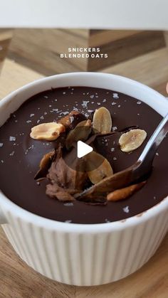 a white bowl filled with chocolate pudding and banana peels on top of a wooden table