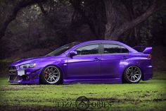 a purple car parked in front of some trees