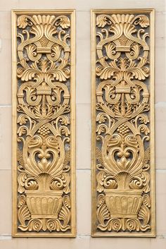 two decorative gold wall panels on the side of a building