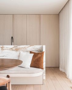 a white couch sitting next to a wooden table in a room with wood flooring