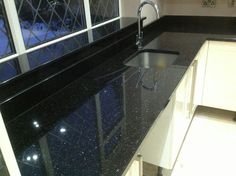 a black counter top in a kitchen next to a sink and window with snow outside