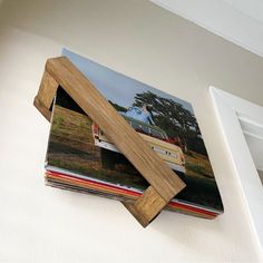 a stack of magazines sitting on top of a white wall next to a wooden frame