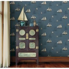 a cabinet in front of a wall with sailboats on it and a blue background