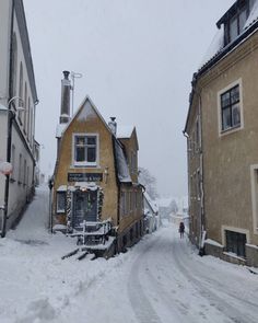 a snow covered street with buildings and people walking on it