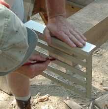 a man is working on a bench with wood shavings in his hands, while another mans hand holds the slats