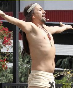 a man with no shirt on is holding his arms out