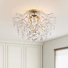 a chandelier hanging from the ceiling in a room with white walls and cabinets