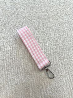 a pink and white checkered umbrella is on the floor next to a pair of scissors